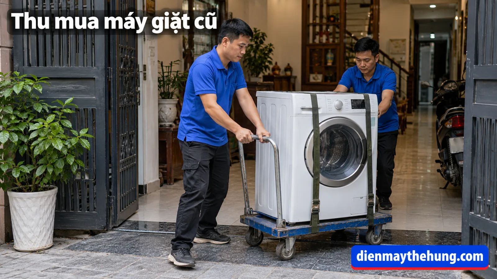 Hai người dùng xe đẩy có dây giữ để đưa máy giặt qua cửa nhà
