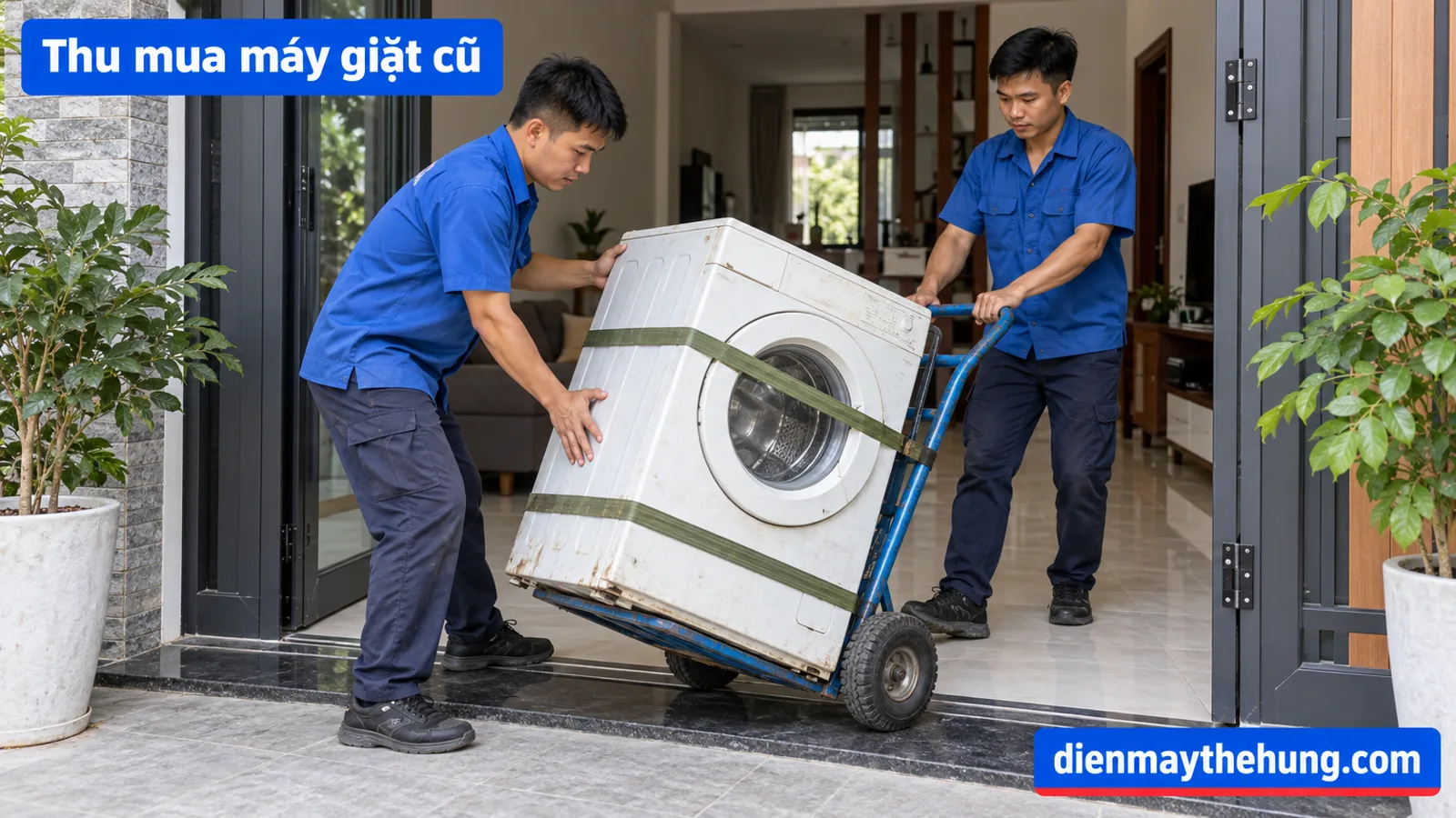 Hai người dùng xe đẩy có dây giữ để vận chuyển máy giặt qua cửa nhà
